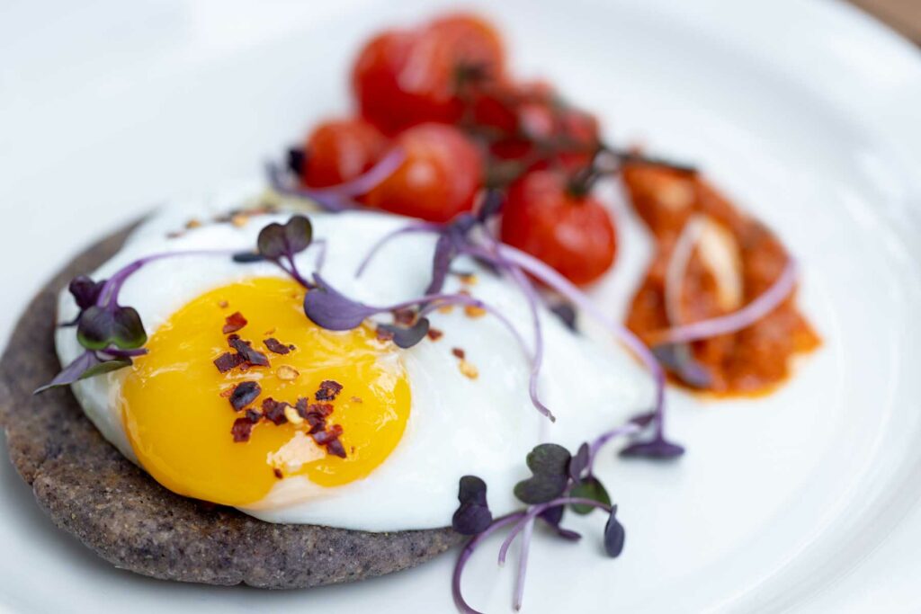 a white plate topped with an egg and tomatoes