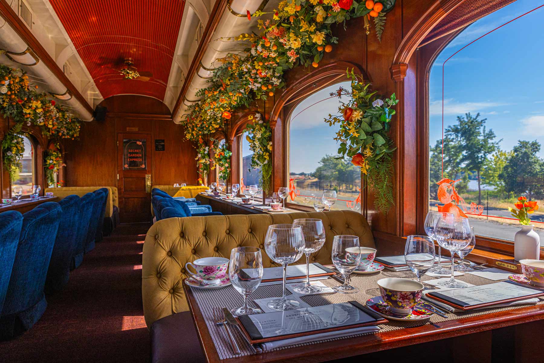 a dining car on a train with flowers hanging from the ceiling