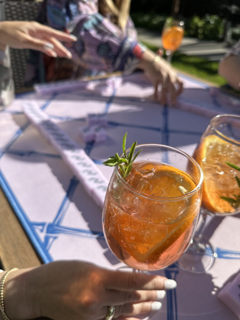 a person holding a wine glass with a sprig of rosemary in it