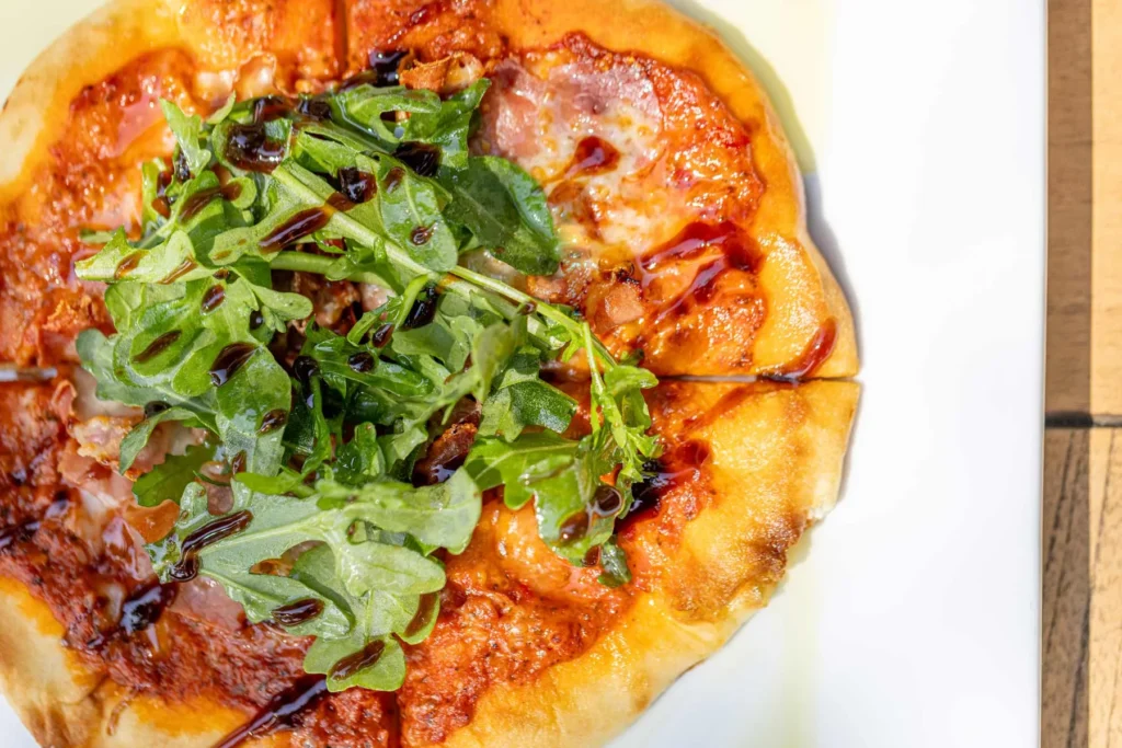 a pizza topped with lots of greens on top of a white plate