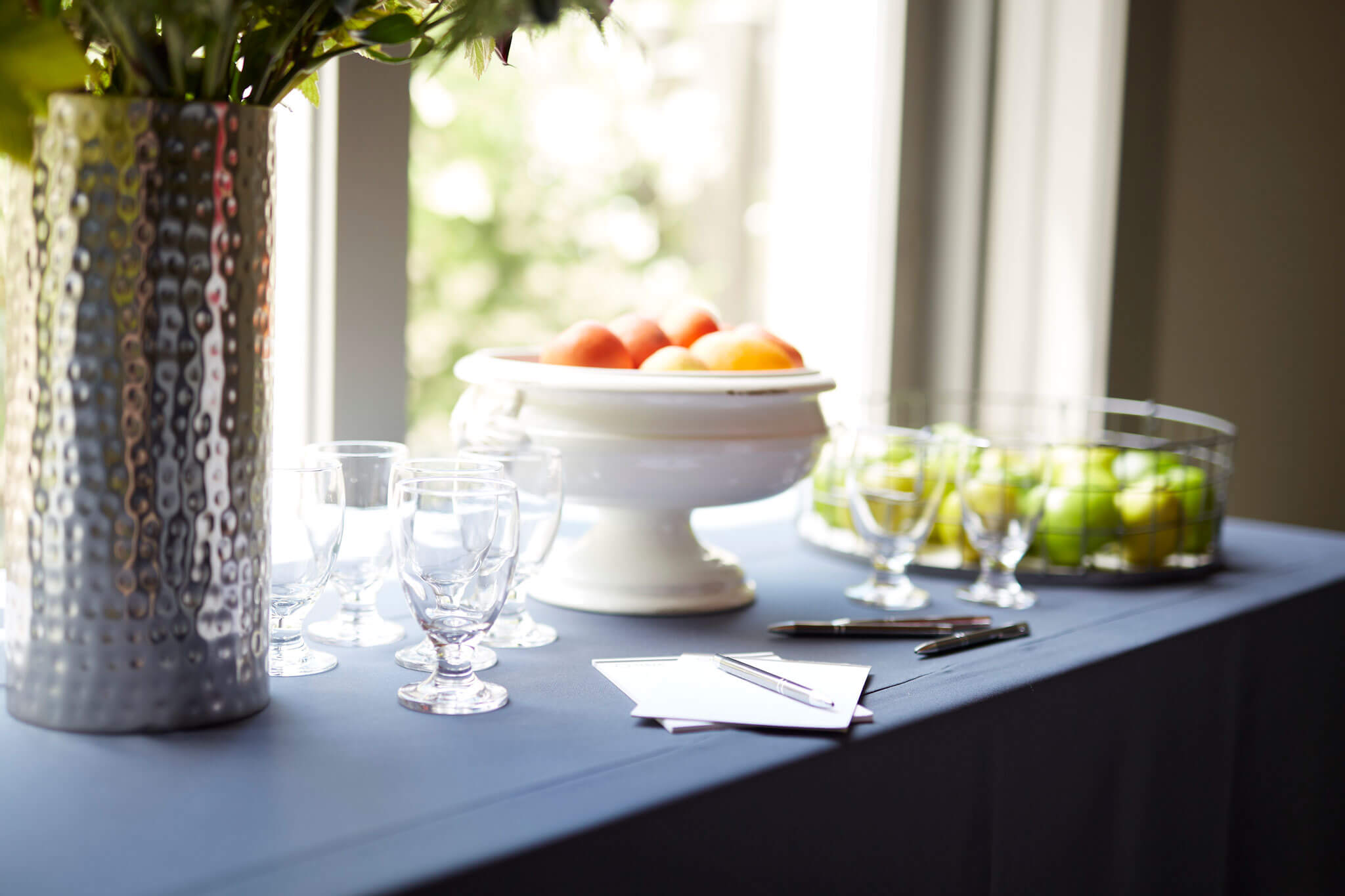 a table topped with a bowl of fruit and glasses