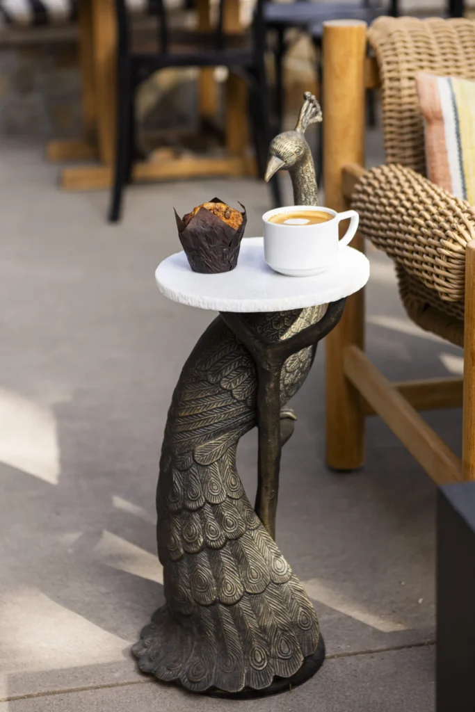 a statue of a bird holding a tray with a cup of coffee on it