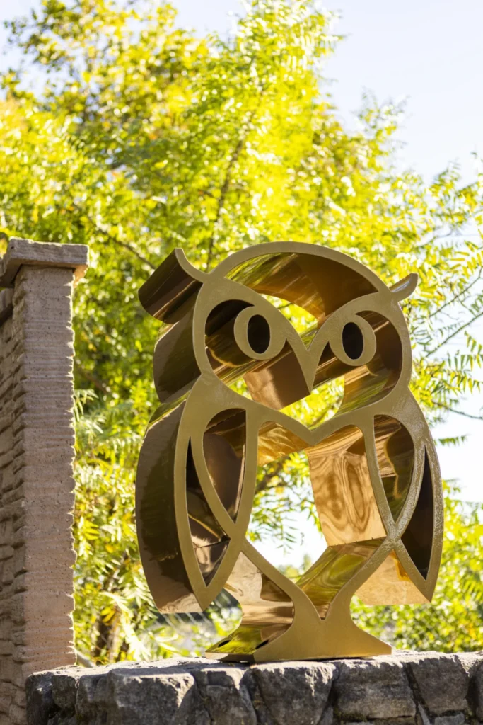 a sculpture of an owl sitting on top of a stone wall