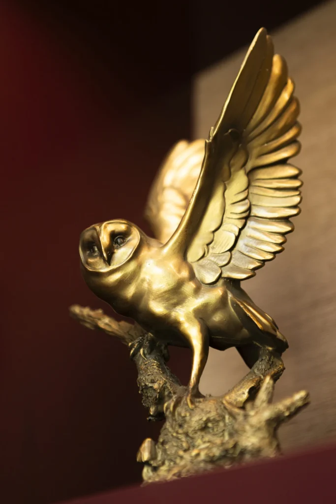 a golden owl statue on a wooden table