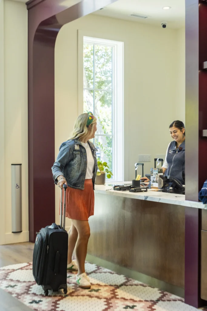 a woman standing in a hotel lobby with her luggage