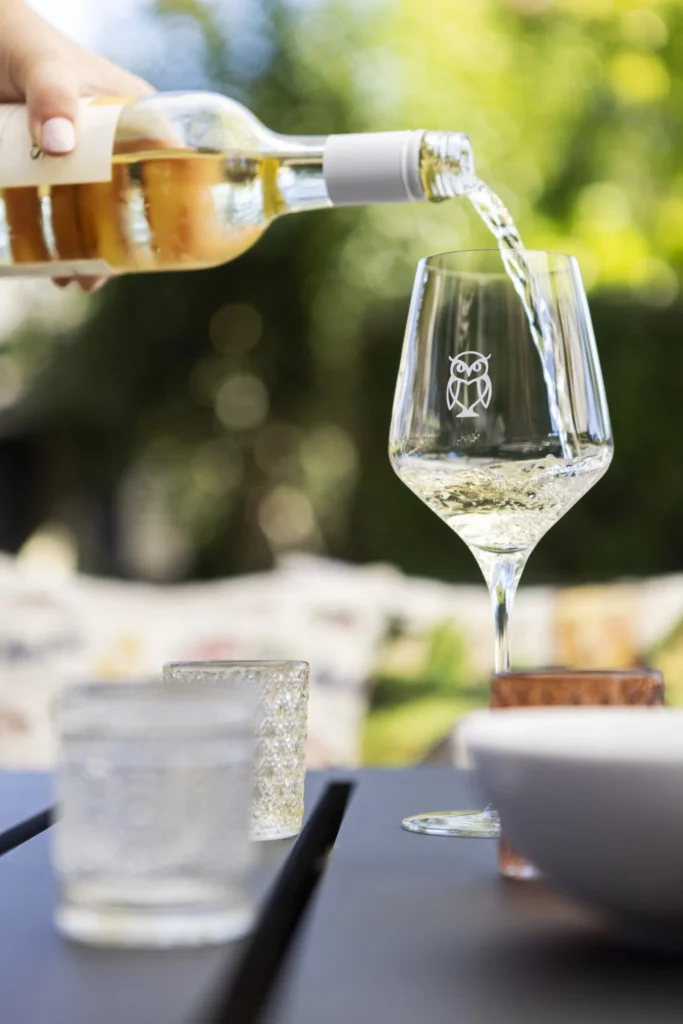 a person pouring wine into a wine glass