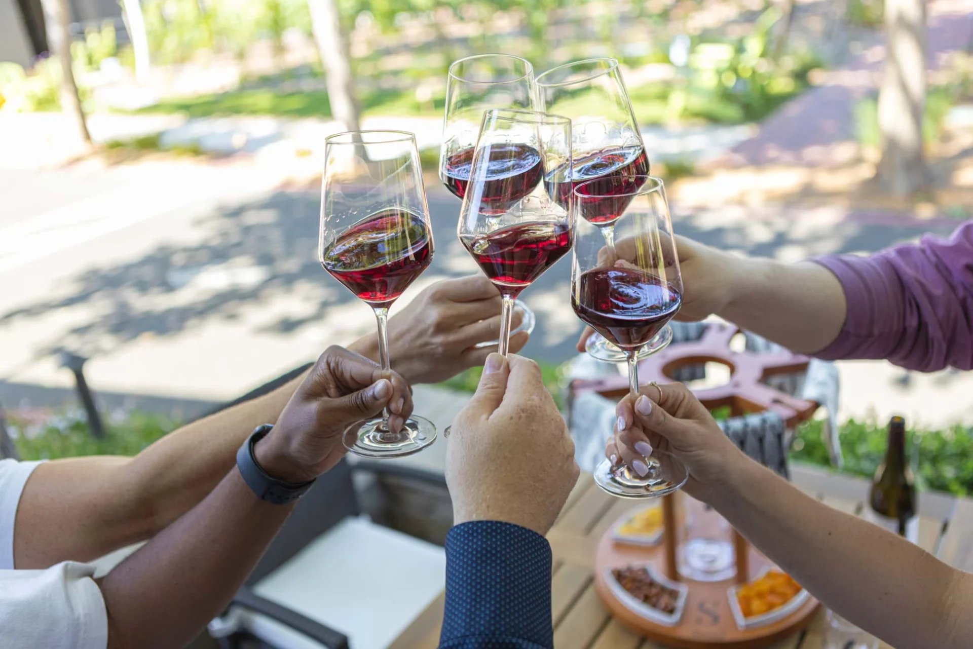 Group of friends toasting red wine glasses together on an outdoor patio, highlighting the Napa Valley experience.