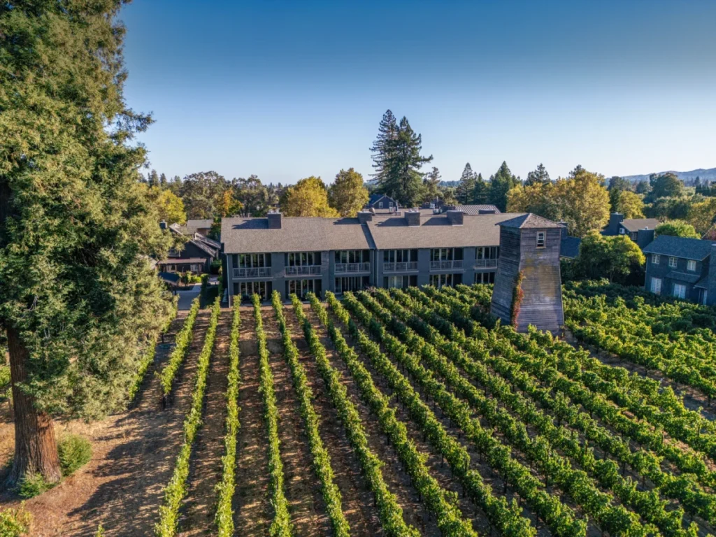 The aerial view of SENZA Hotel shows the gray guest building nestled among the scenic Napa Valley vineyards.