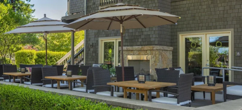 a patio with tables and chairs and an umbrella