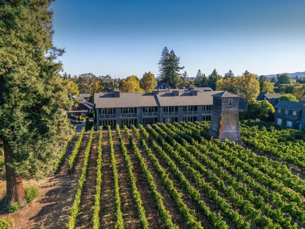 The aerial view of SENZA Hotel shows the gray guest building nestled among the scenic Napa Valley vineyards.