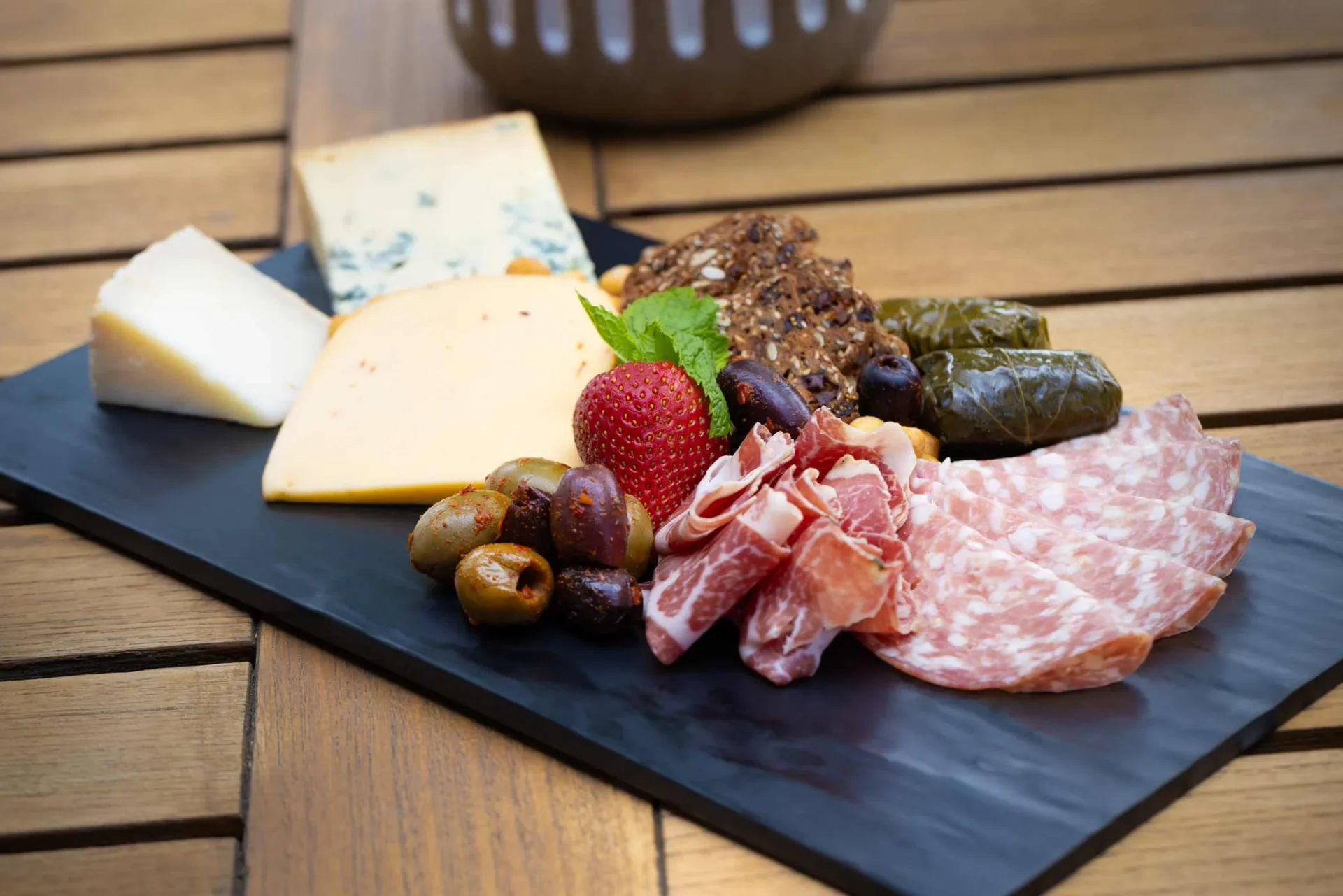 a plate of meats, cheeses, and fruit on a table