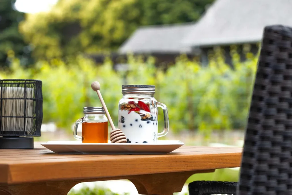 a wooden table topped with a plate of food and a jar of honey