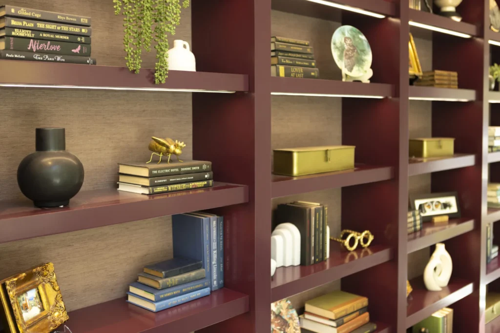 a bookshelf filled with lots of books next to a vase