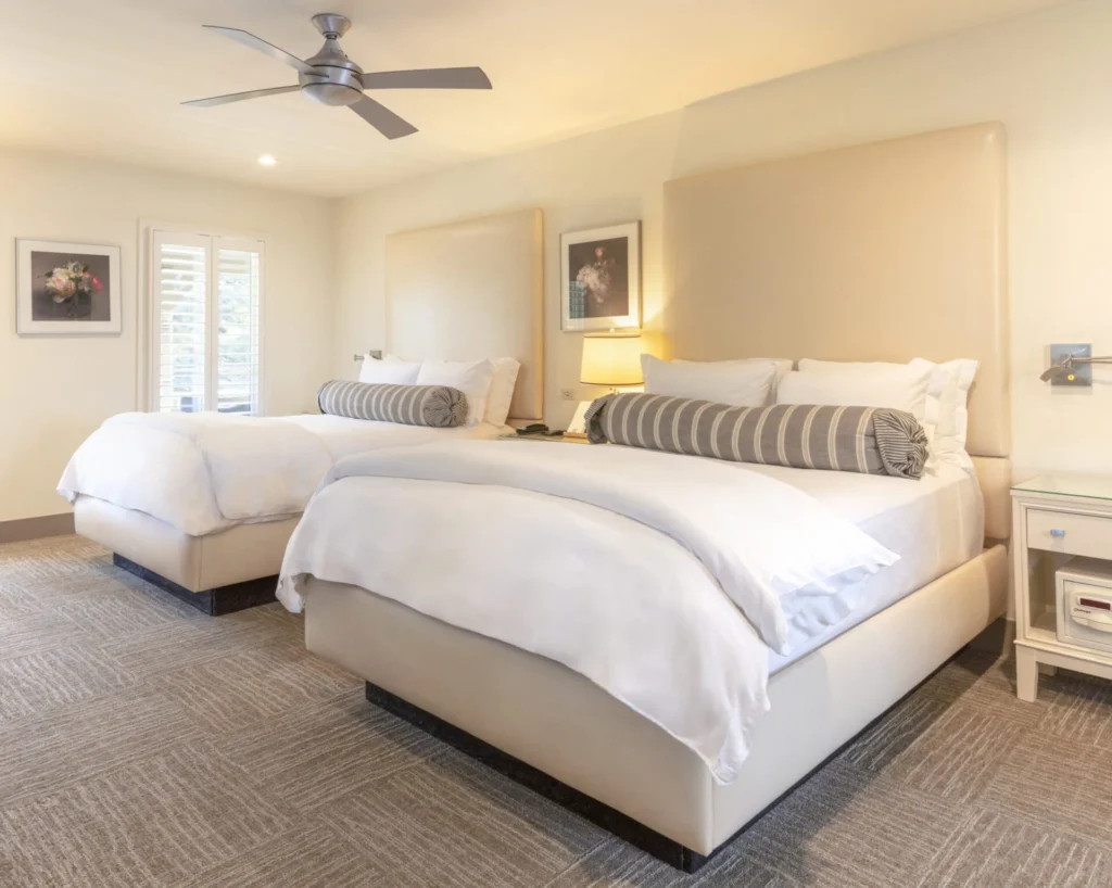 a bedroom with two beds and a ceiling fan