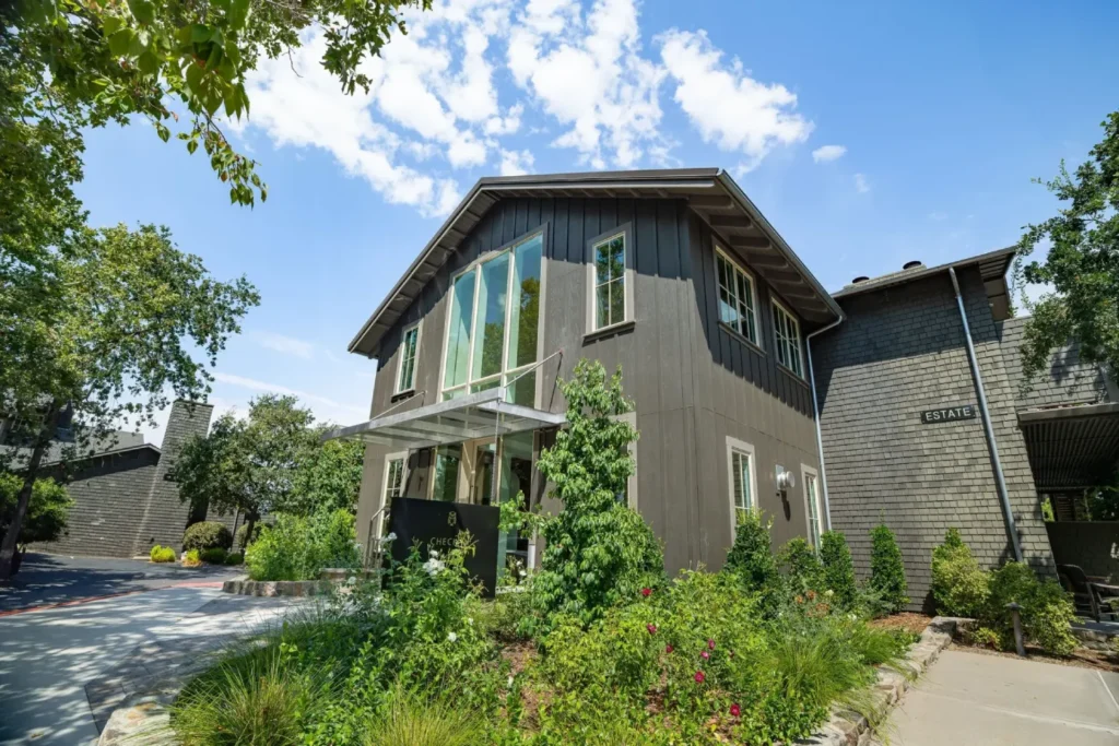 A house with a lot of trees and bushes in front of it