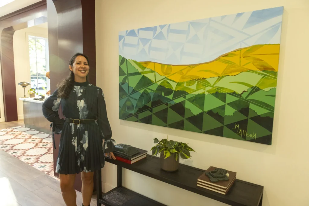 a woman standing next to a painting on a wall