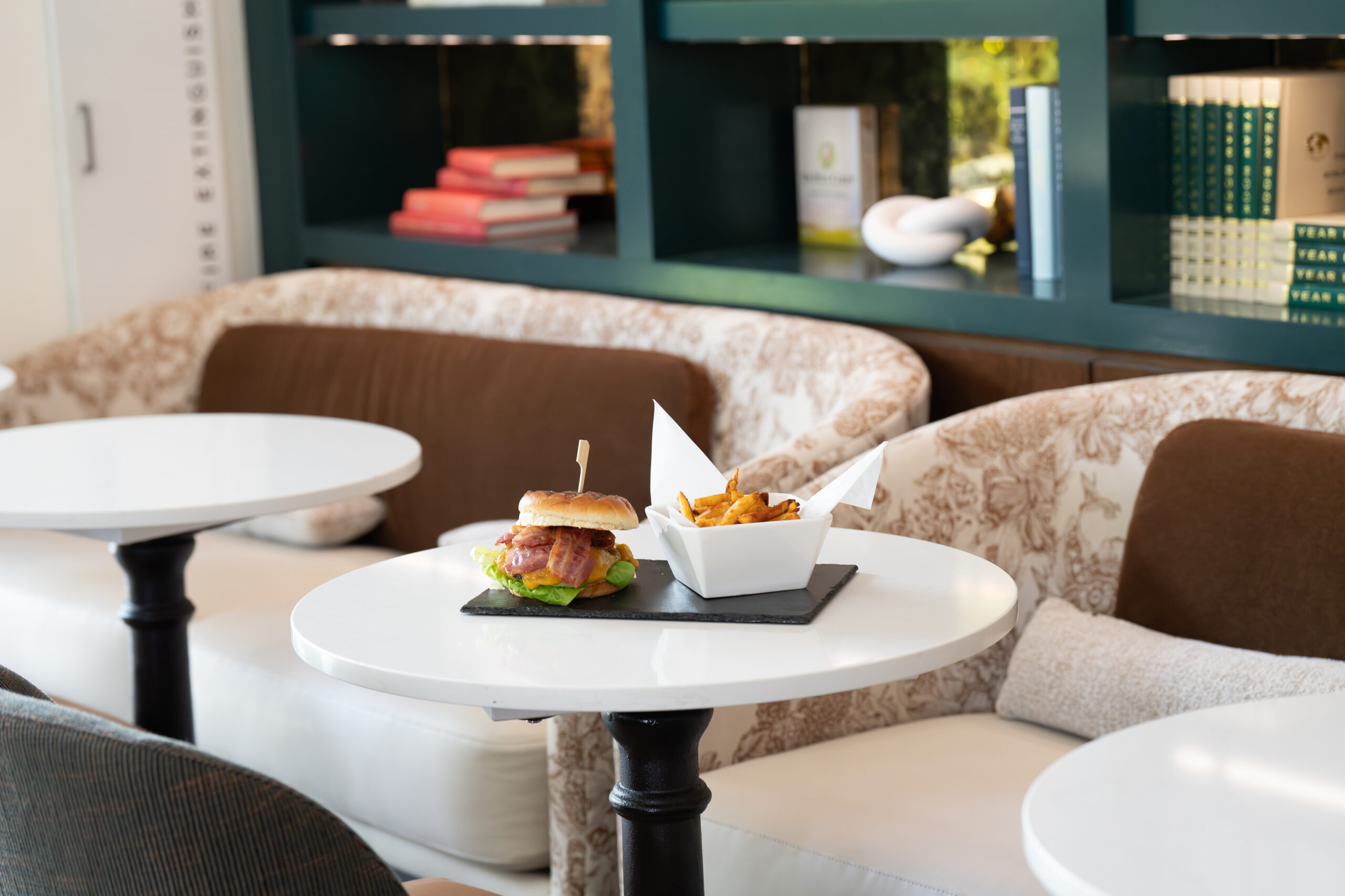 Bacon cheeseburger and seasoned fries served on a table inside The Study lounge at SENZA Hotel in Napa Valley.