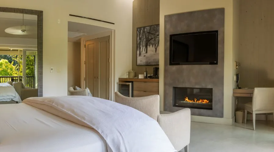 Modern hotel bedroom featuring a white bed, fireplace, and wall-mounted TV at Senza Hotel
