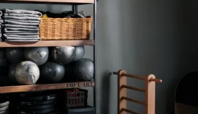 Shelves with folded towels, wicker baskets, and medicine balls next to a wooden rack