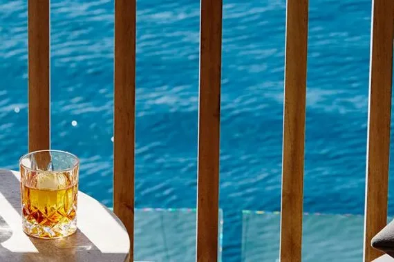 Whiskey glass on balcony overlooking blue sea