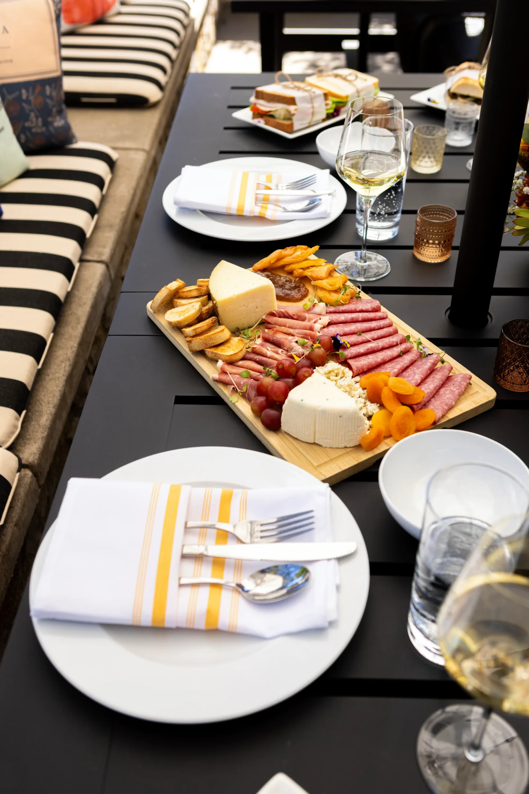 Outdoor dining table featuring a charcuterie board, white plates, and wine glasses at Senza Hotel.