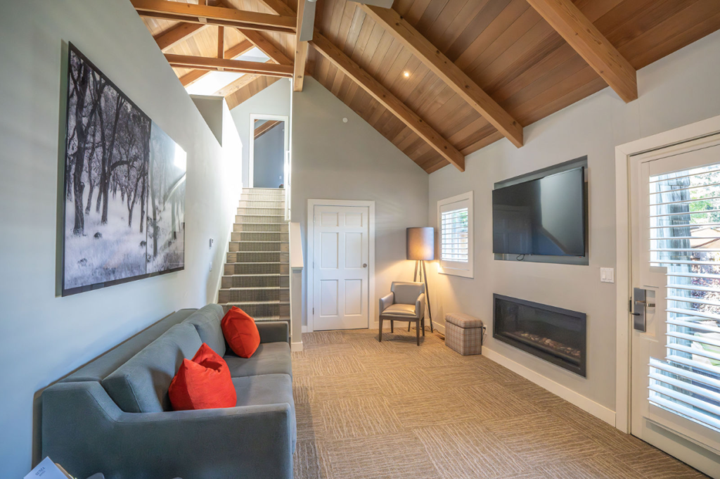 Modern living room with vaulted wood ceiling, grey sofa, and fireplace