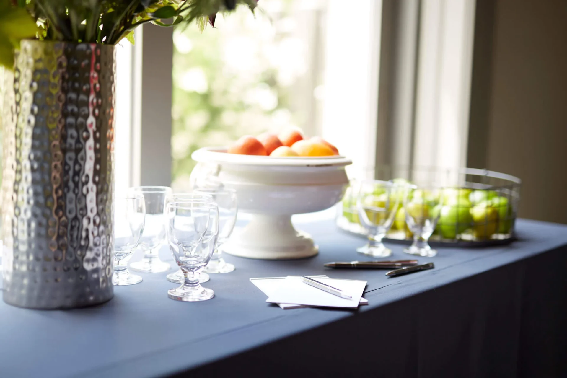 Elegant table setup with silver vase, fruit bowls, and glasses at Senza Hotel