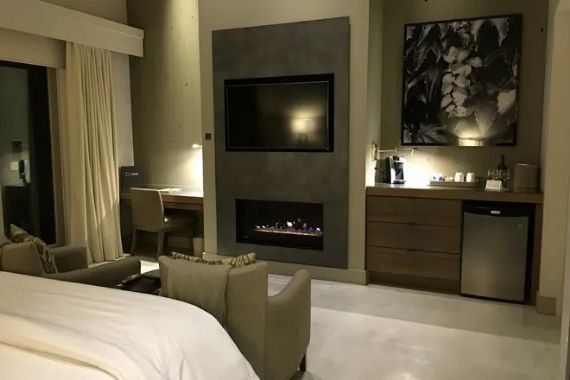 Modern hotel room interior with fireplace, TV, and seating area
