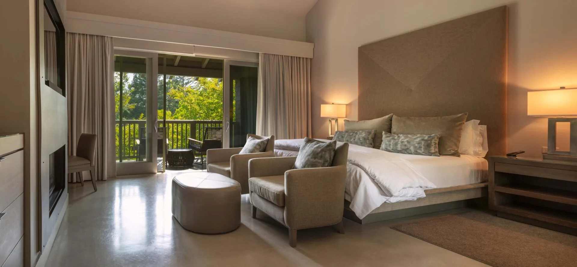 Spacious hotel suite with king bed, seating area, and balcony access