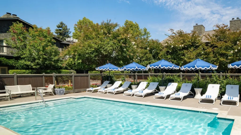 Outdoor pool with blue umbrellas and lounge chairs at Senza Hotel