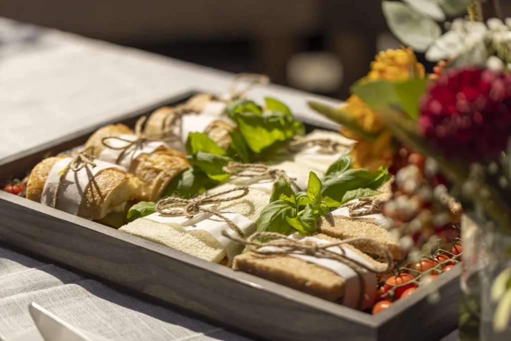 Wooden tray of sandwich rolls tied with twine and garnished with basil